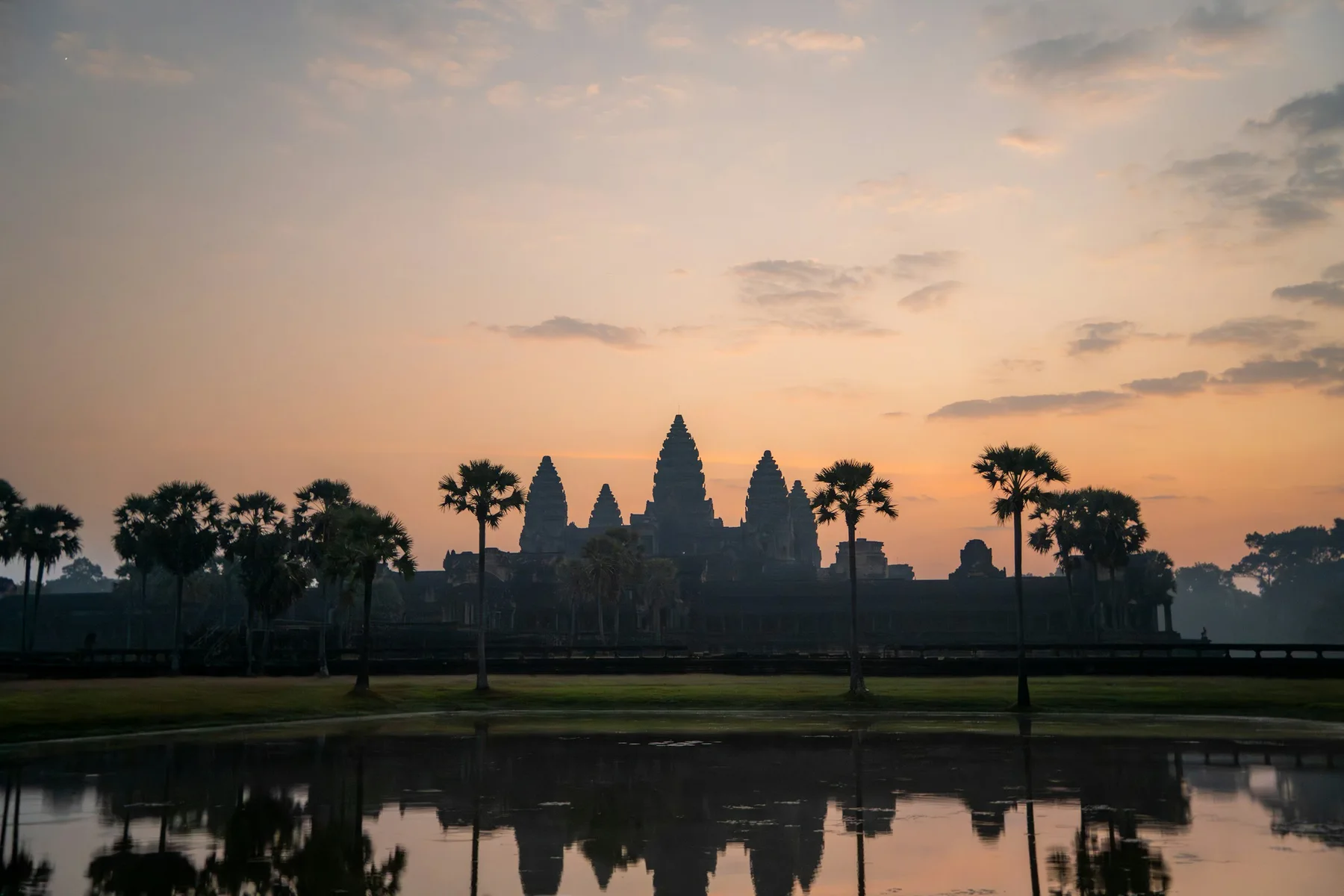Angkor Wat towers reflected in still water at sunrise